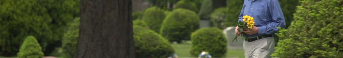 older-man-walking-through-cemetery-holding-flowers_41fe6yf0__F0000